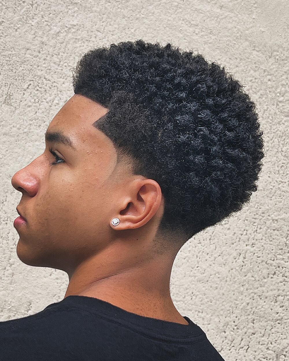 Short afro with low taper fade and defined hairline for coily textured men’s hair