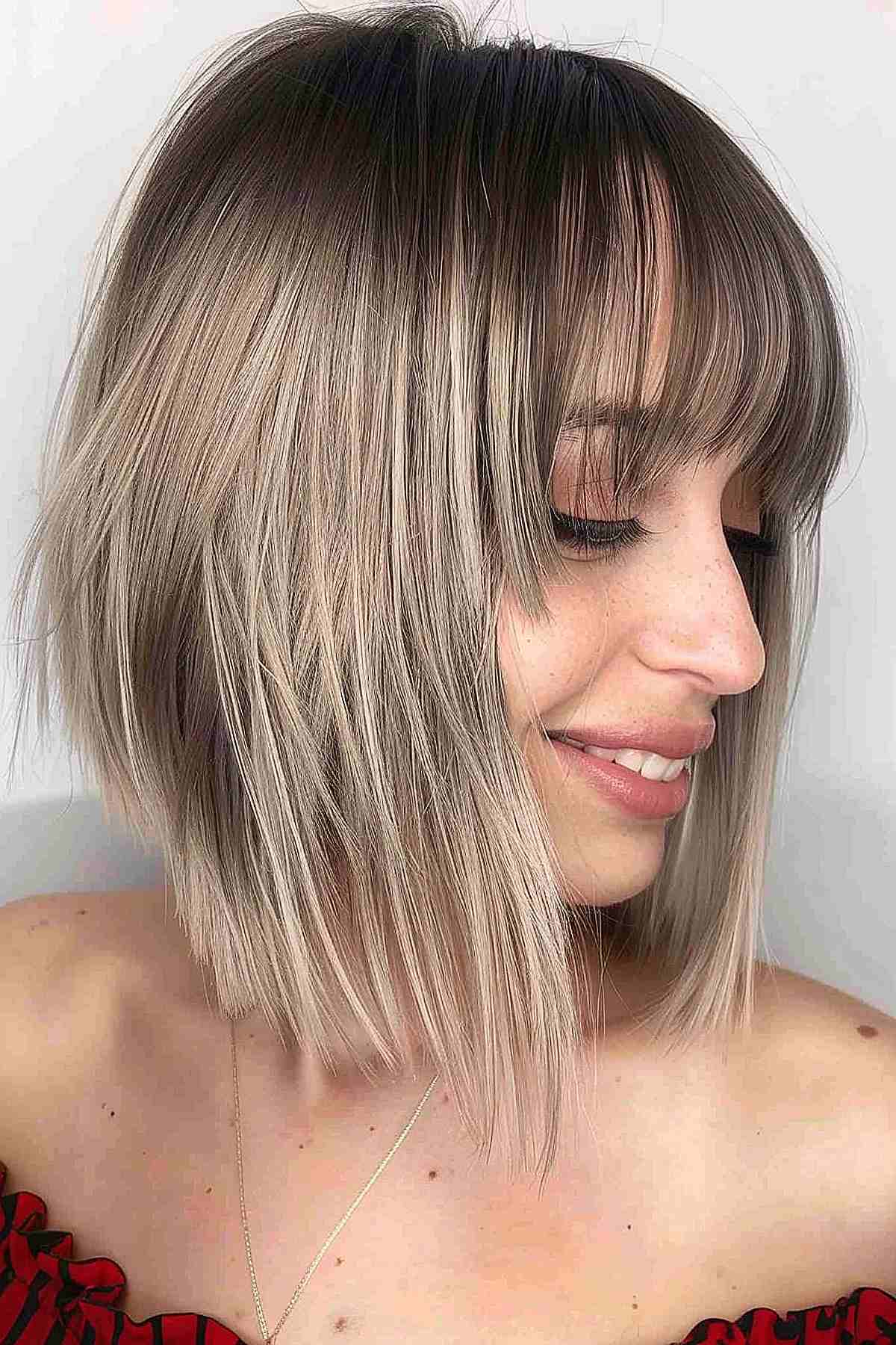 Woman with a tapered blonde bob and long bangs showing dark to light color gradient