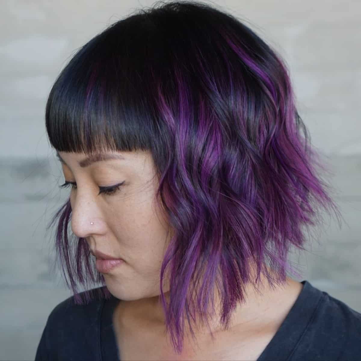 Textured angled bob with bangs and purple highlights