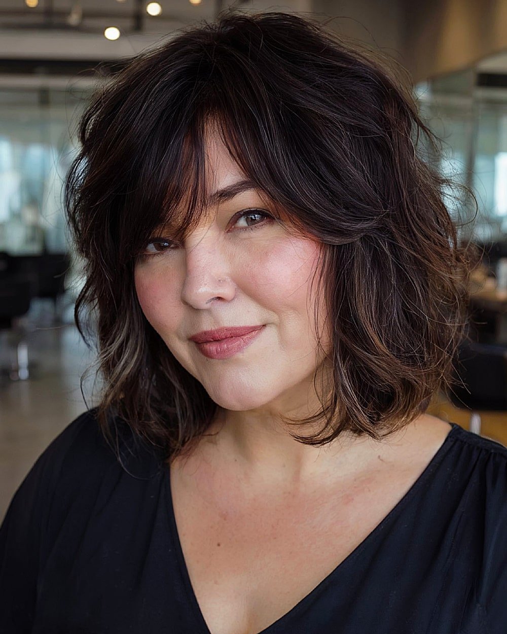 Textured brunette cut with tousled layers and long side bangs for round faces over 40