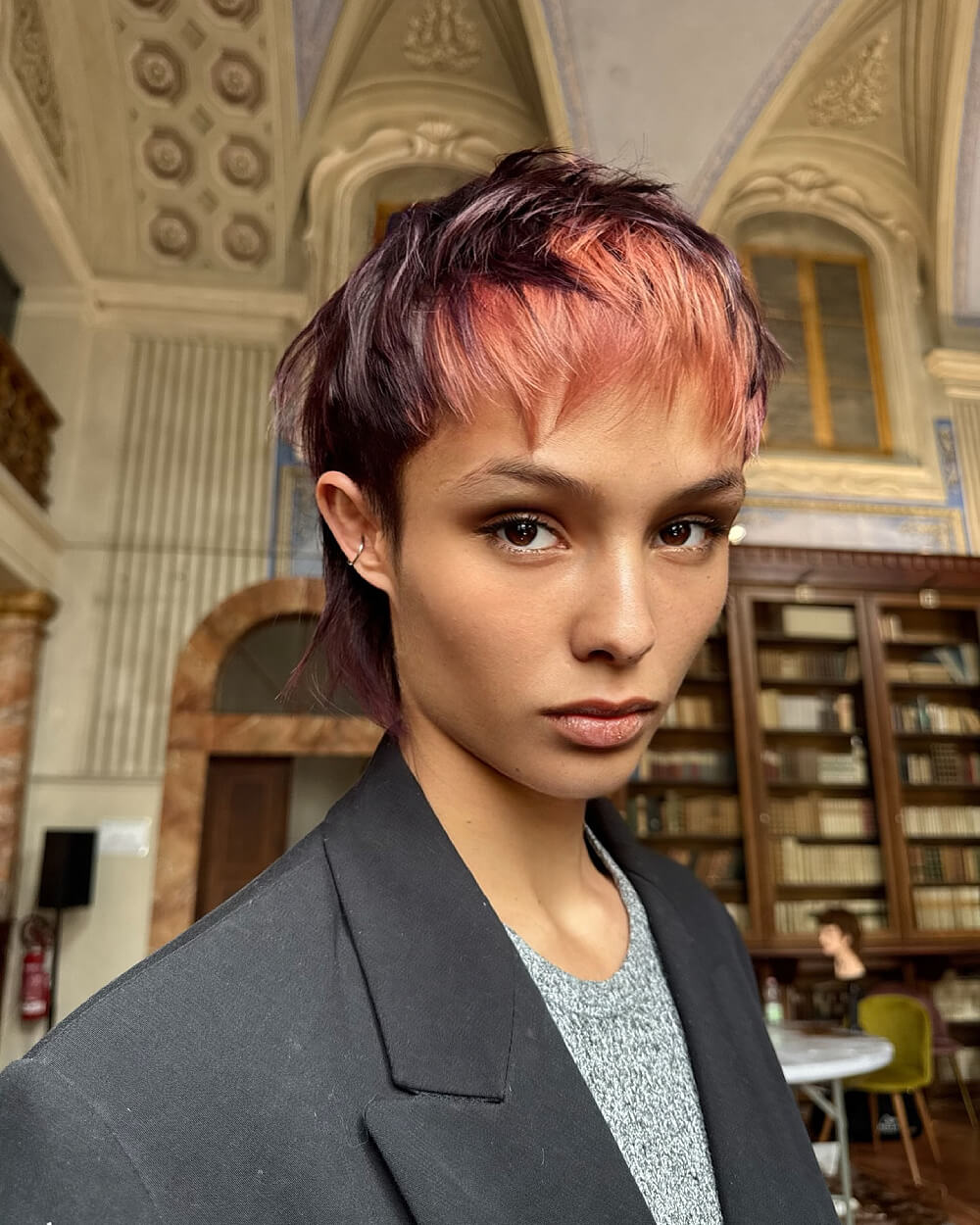 Textured pixie mullet with choppy layers and peach highlights over dark plum hair