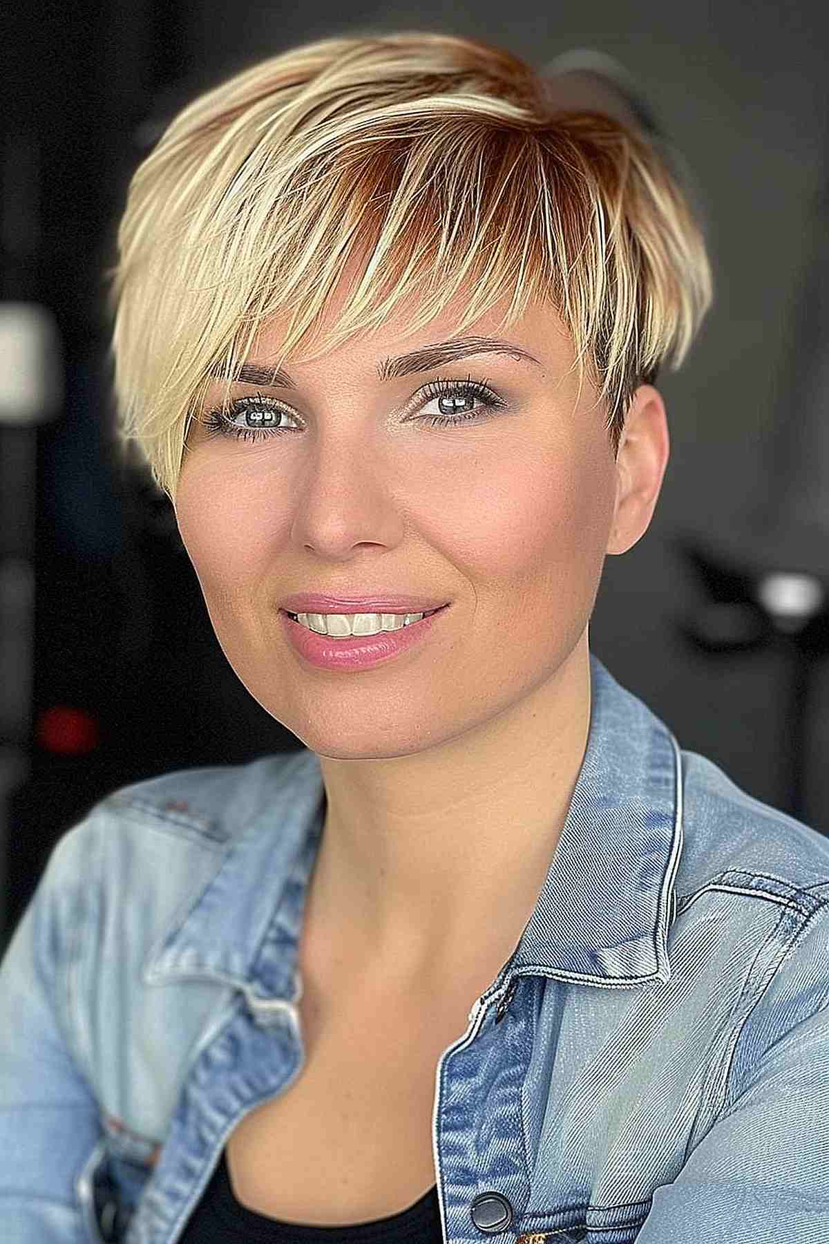 Close-up of a woman with a textured pixie haircut featuring an asymmetric fringe, styled in a modern and edgy manner.