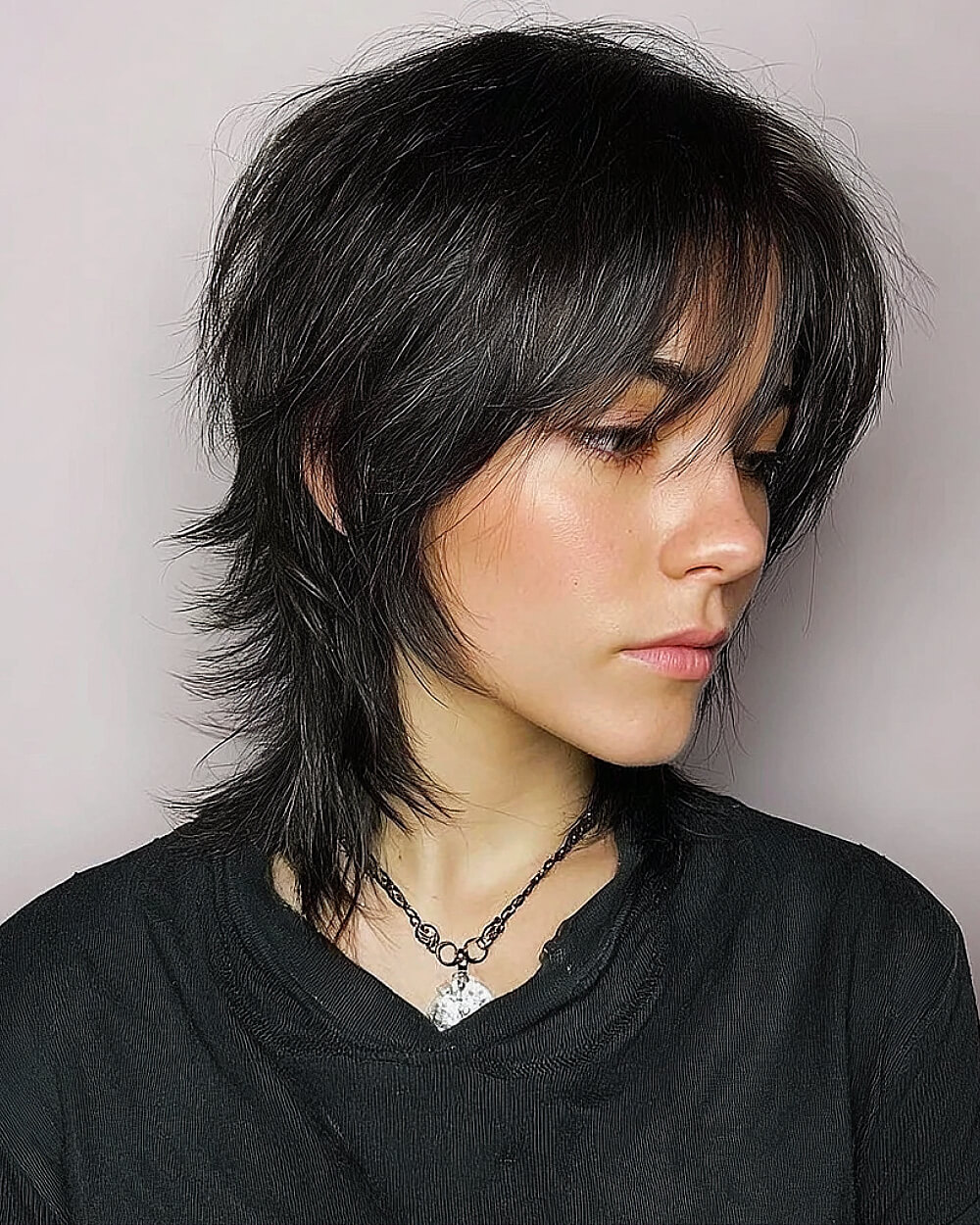 Textured short wolf cut with shaggy layers and curtain bangs on straight dark hair