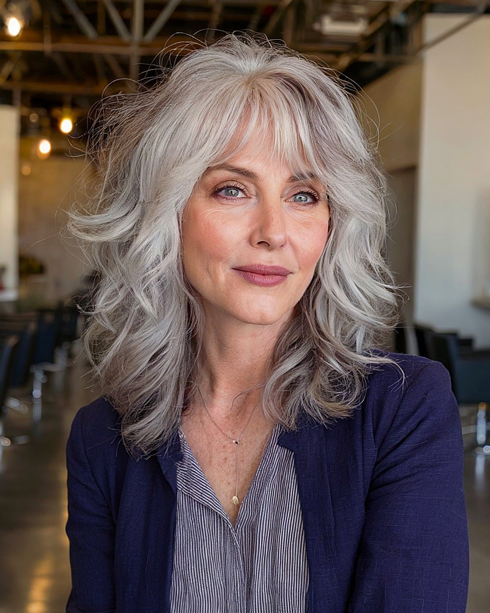 Silver layered hairstyle with wispy bangs and tousled texture for naturally wavy, mature hair