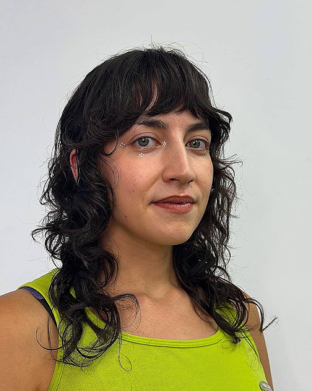 Textured wolf cut with tousled bangs on medium curly hair for a modern layered hairstyle