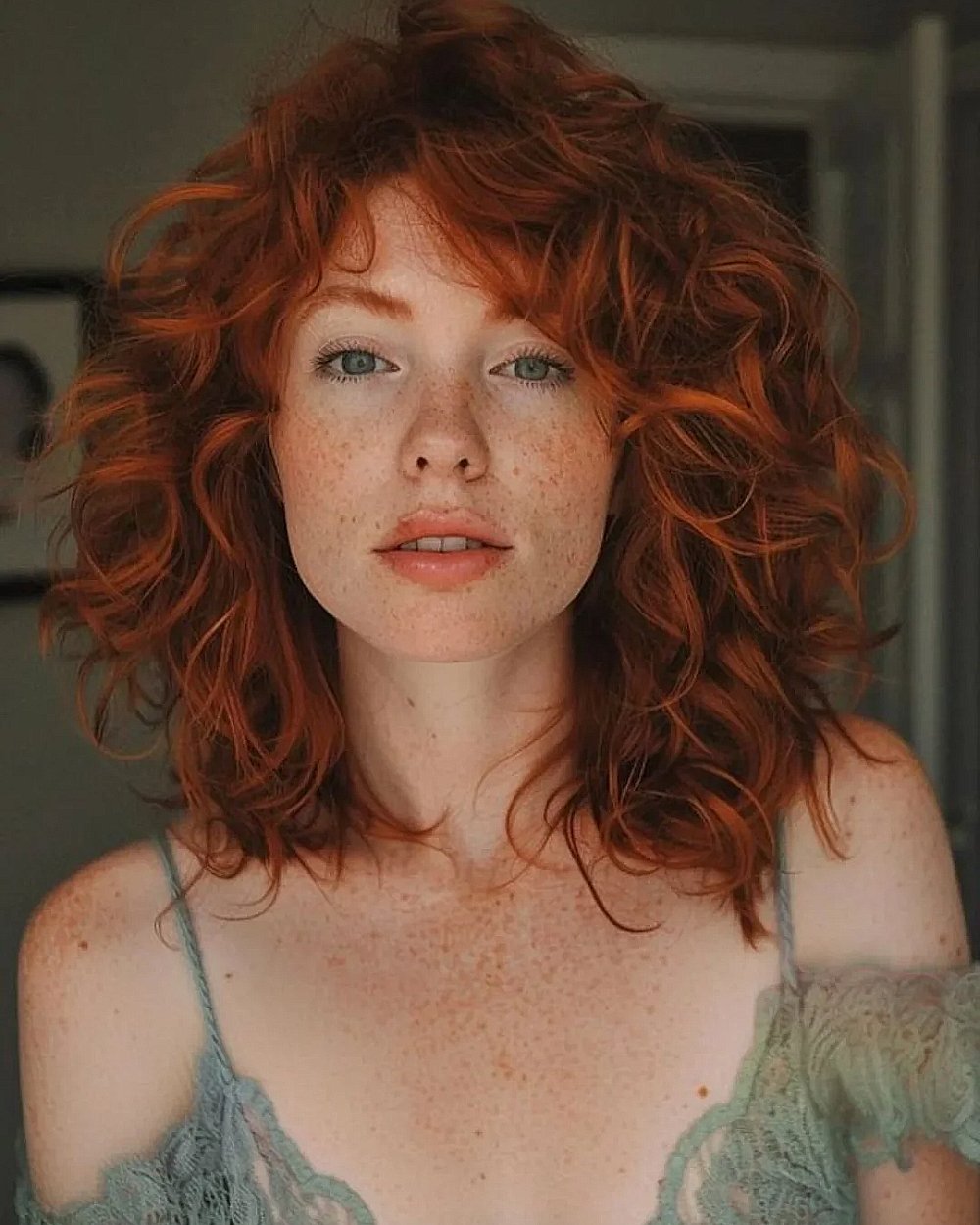Tousled copper curls with fringe, medium-length fall hairstyle with natural volume and soft layers