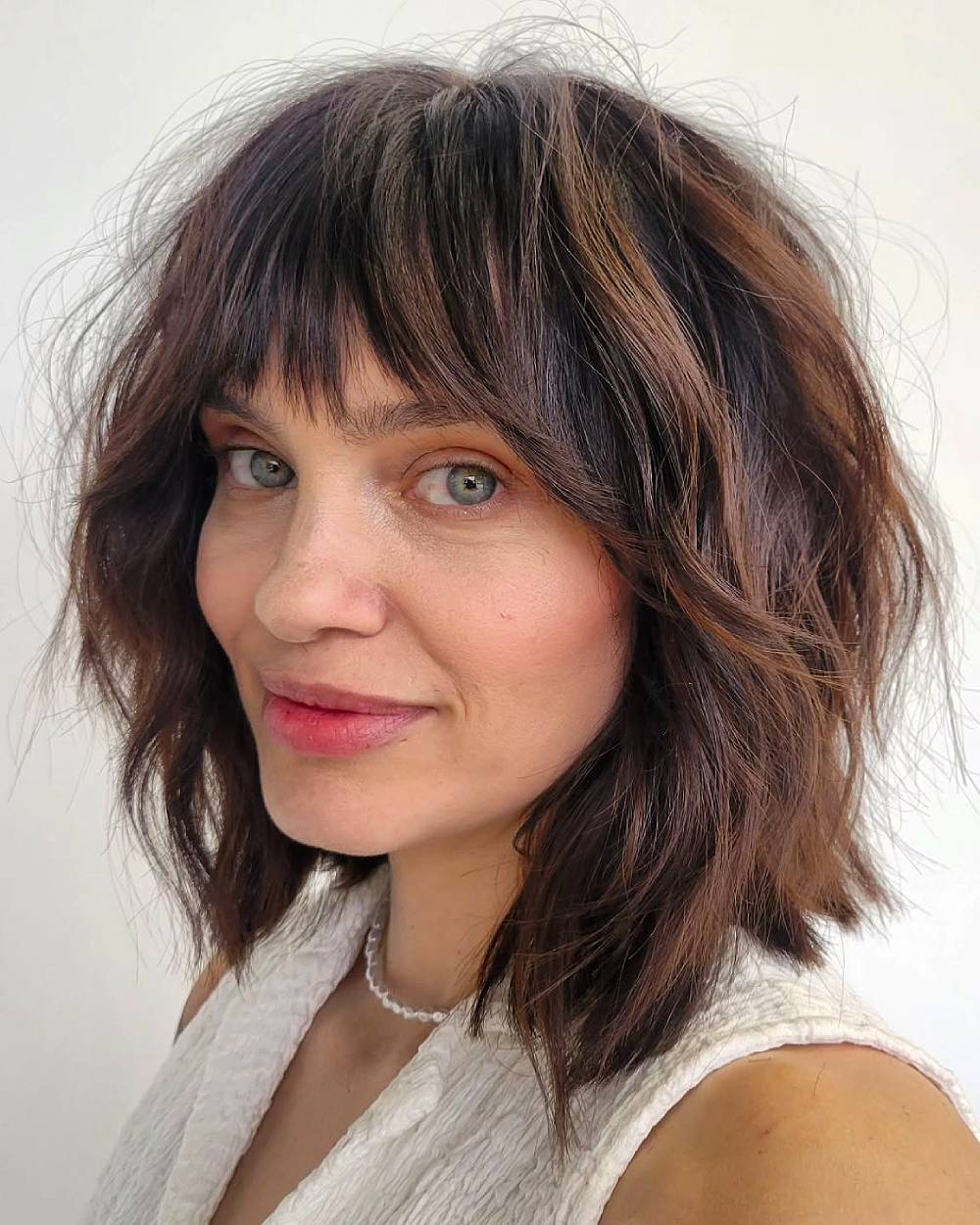 Shoulder length tousled shag with choppy bangs and textured layers for thick, wavy hair