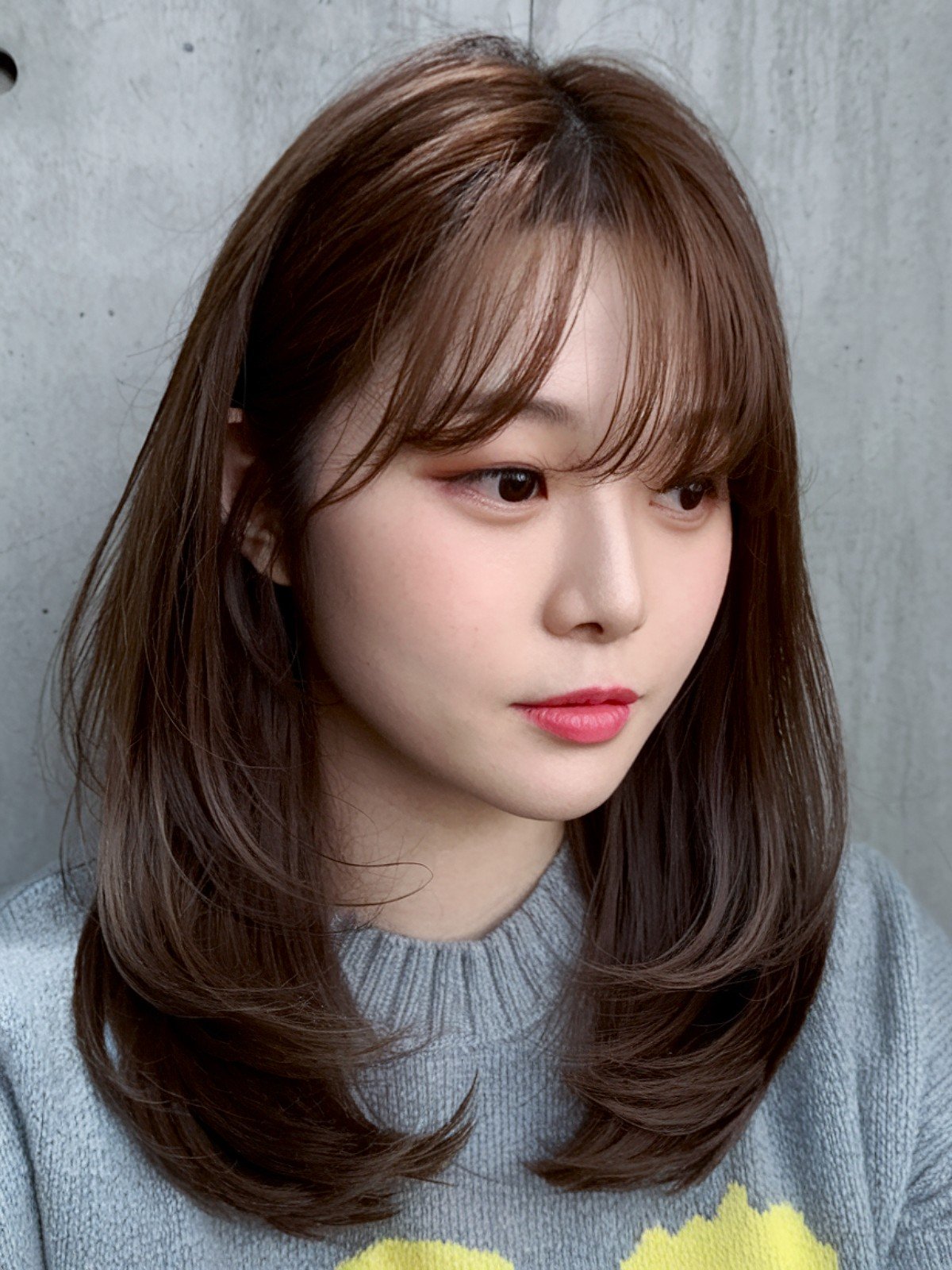 Korean-style layered haircut with sleek layers and wispy bangs