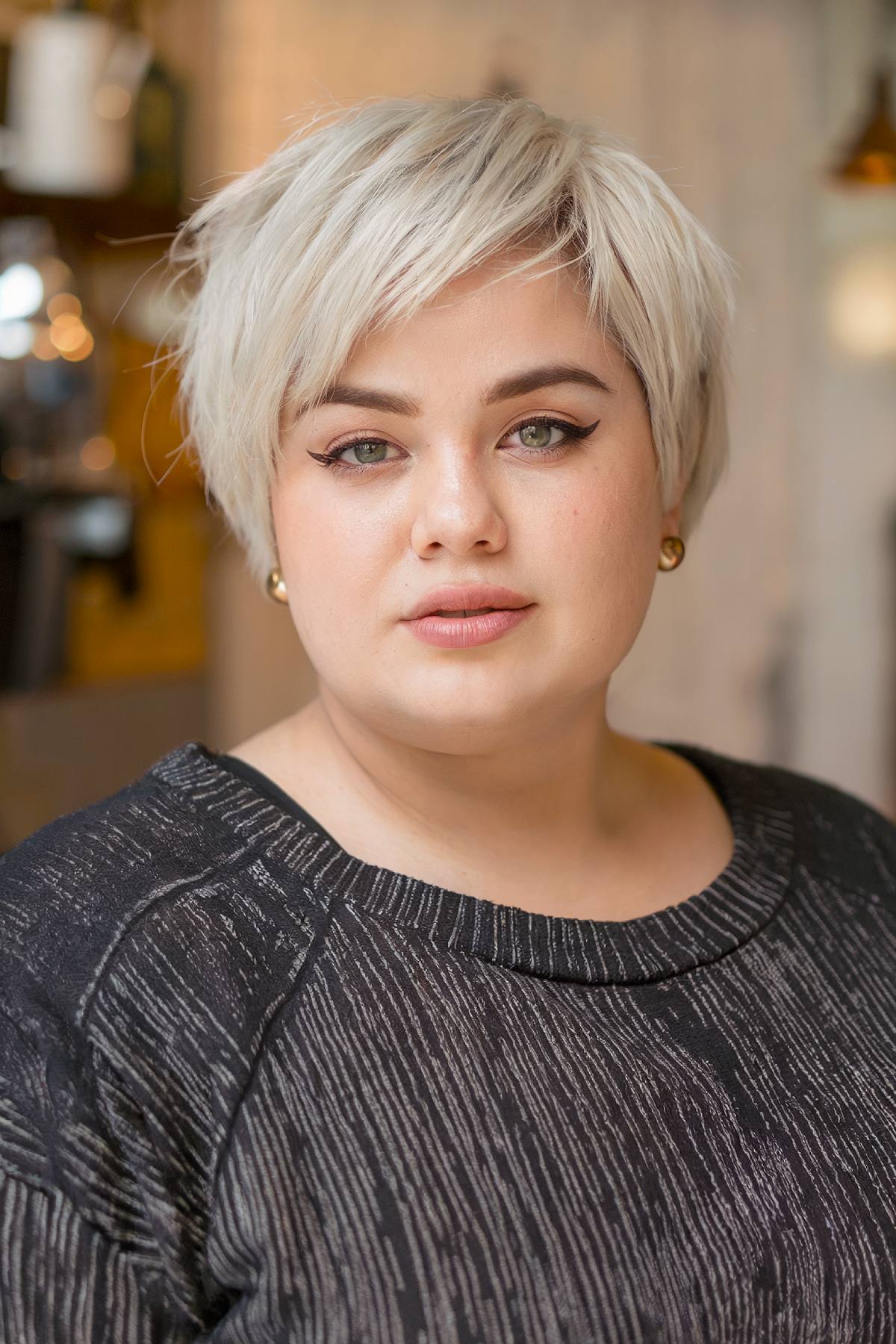 Short pixie bob haircut with feathered bangs for round face shapes