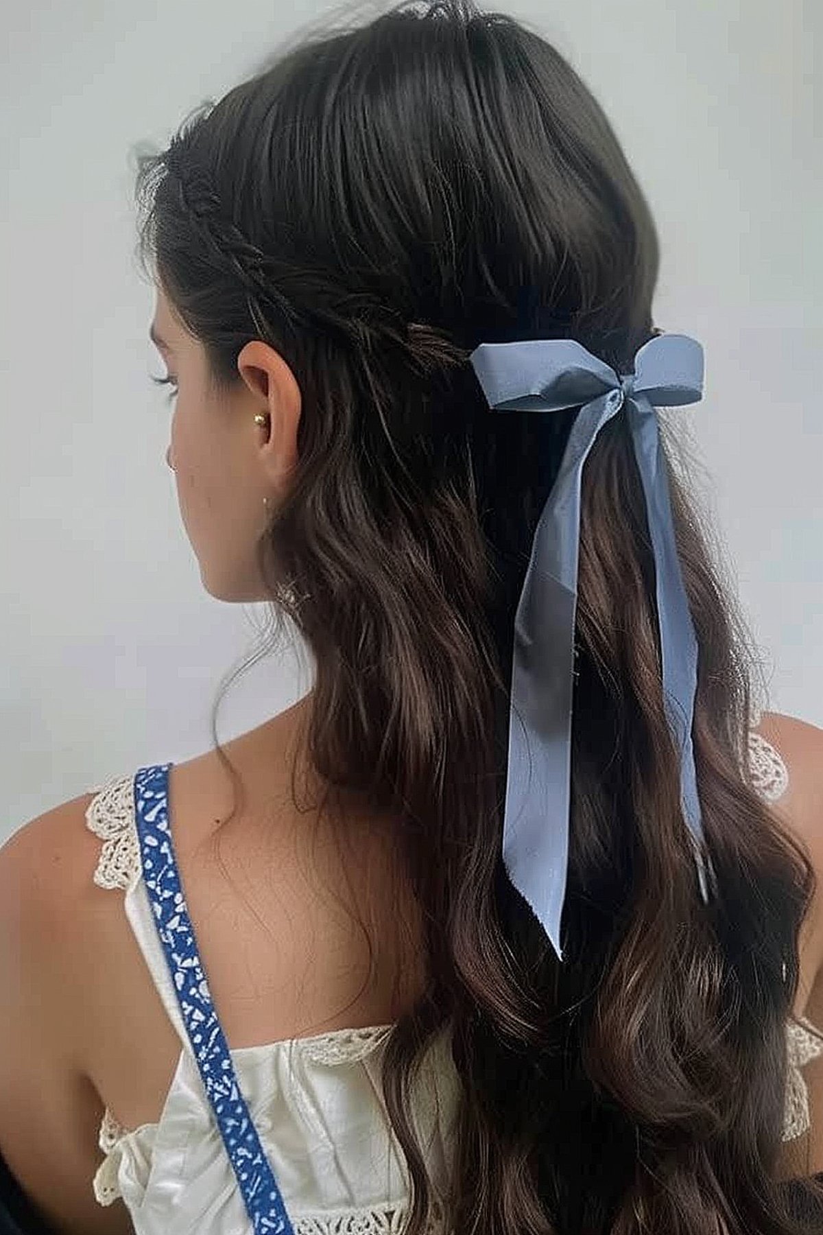 Twisted half-up hairstyle with blue ribbon accent for summer