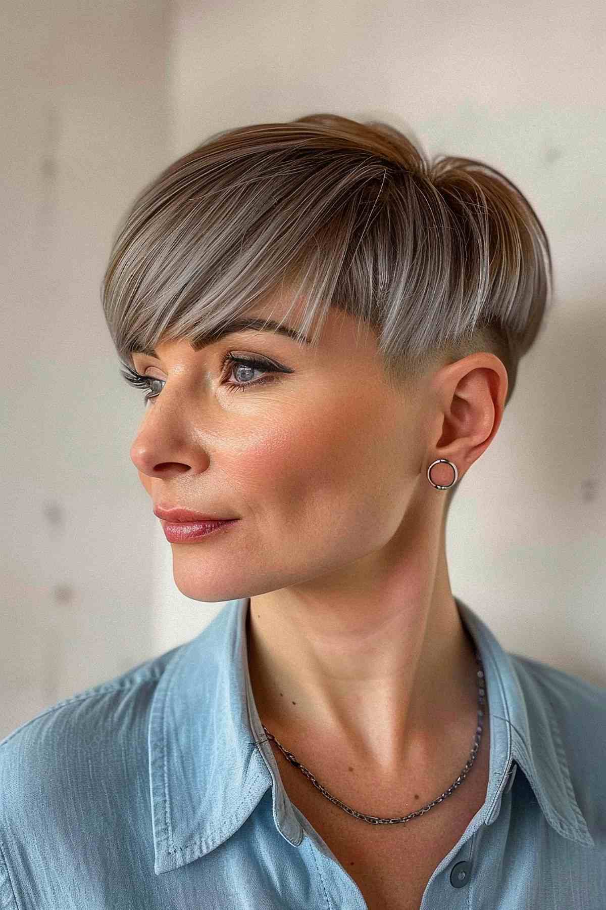 Woman with an undercut pixie bob and bold bangs, profile view.