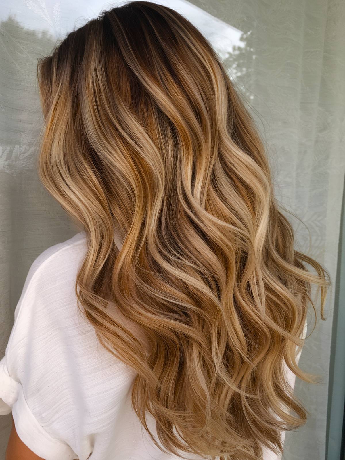 Blonde caramel balayage on brunette hair for a sunlit effect