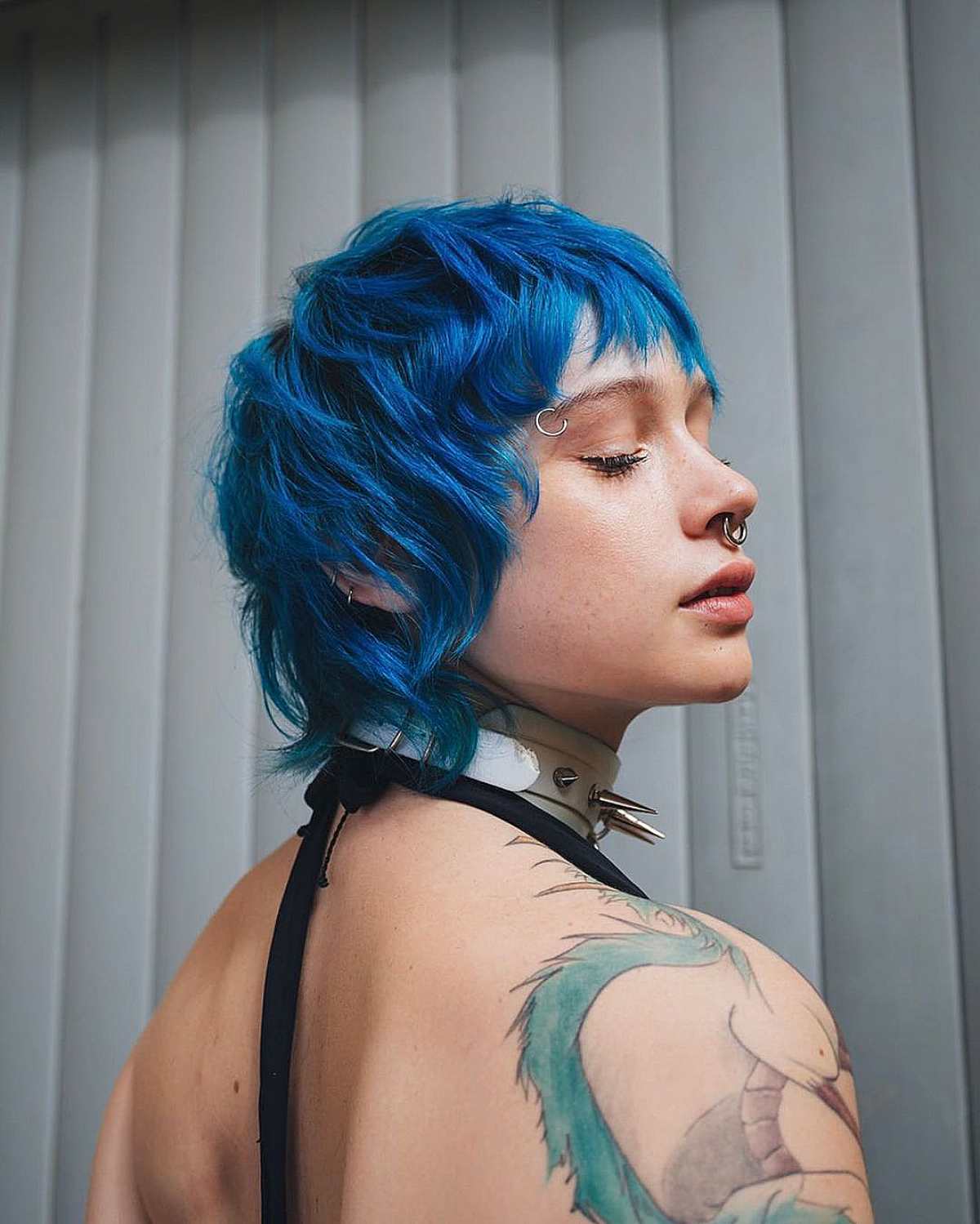Vibrant blue shag haircut with textured layers and choppy fringe on thick, wavy hair