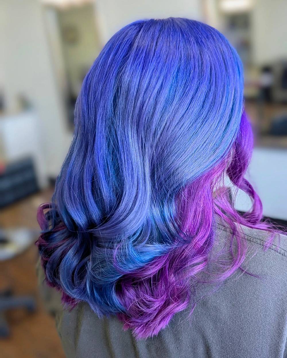 Violet and magenta hair color melt with blue accents on medium-length wavy hair