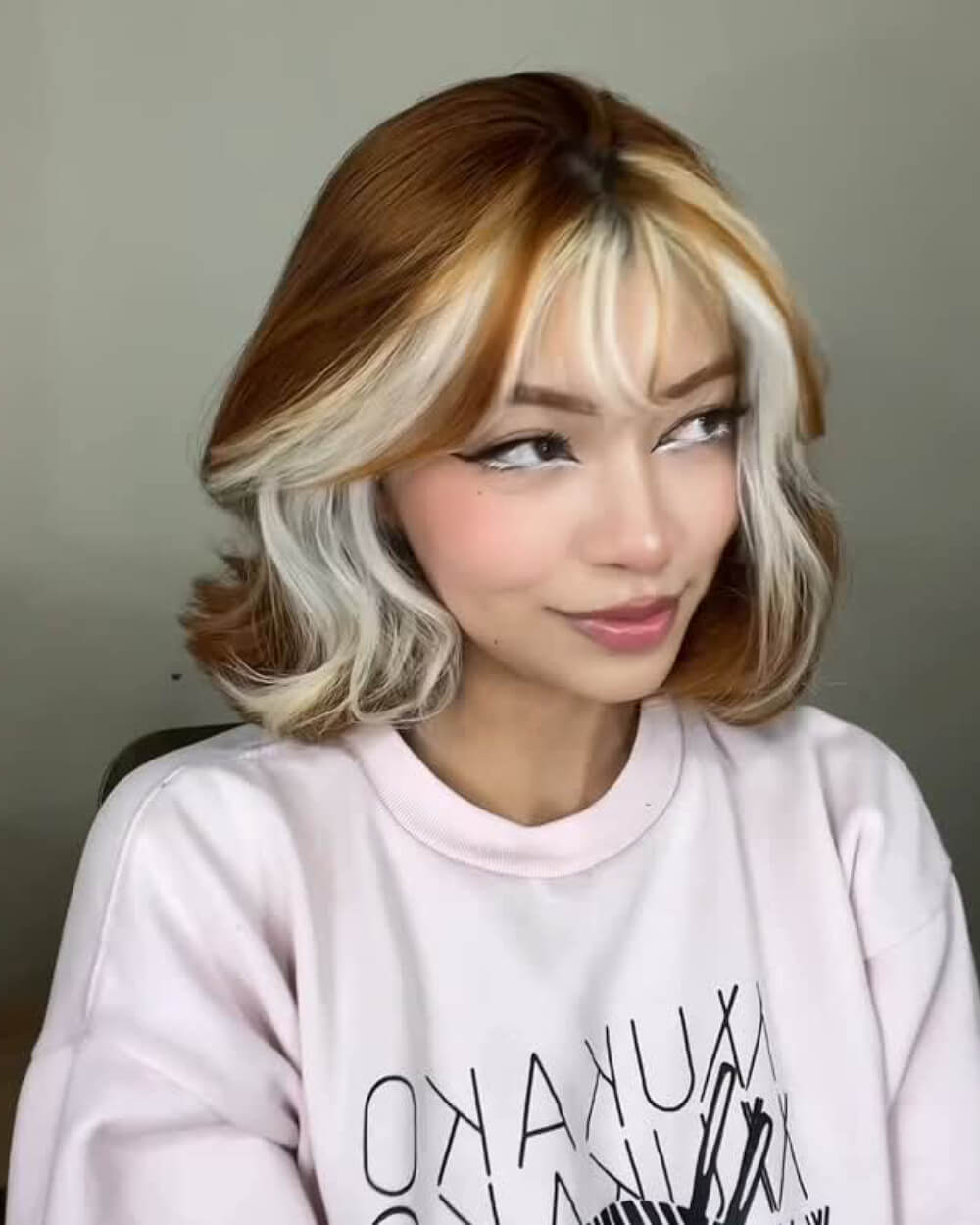 Voluminous Gemini bob with copper brown base and bold blonde face-framing highlights