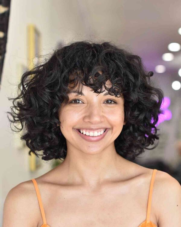 A Voluminous Curls with Bangs for Round Faces