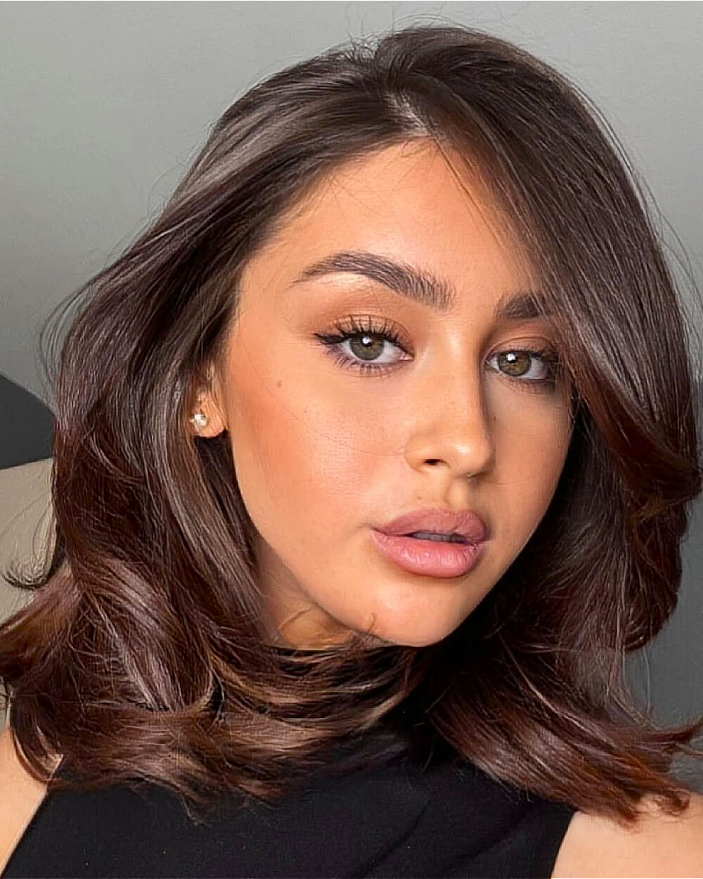 Voluminous long bob with flipped-out ends and smooth layers on thick brunette hair