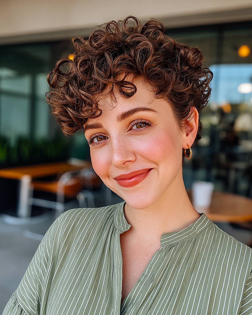 Voluminous curly pixie cut with defined short curls and soft bangs for thick natural curly hair