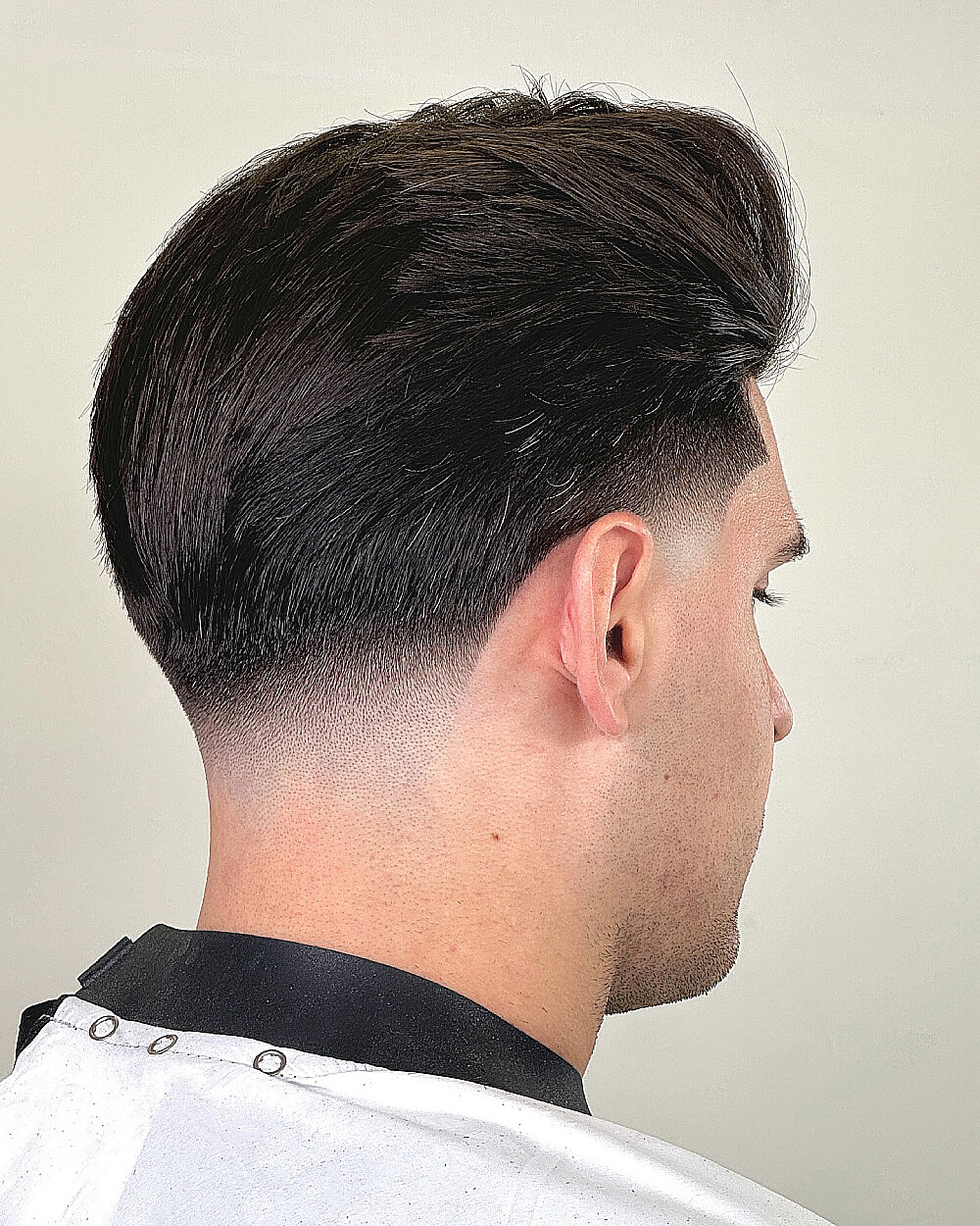 Men’s voluminous pompadour with sharp low taper fade for thick, styled hair