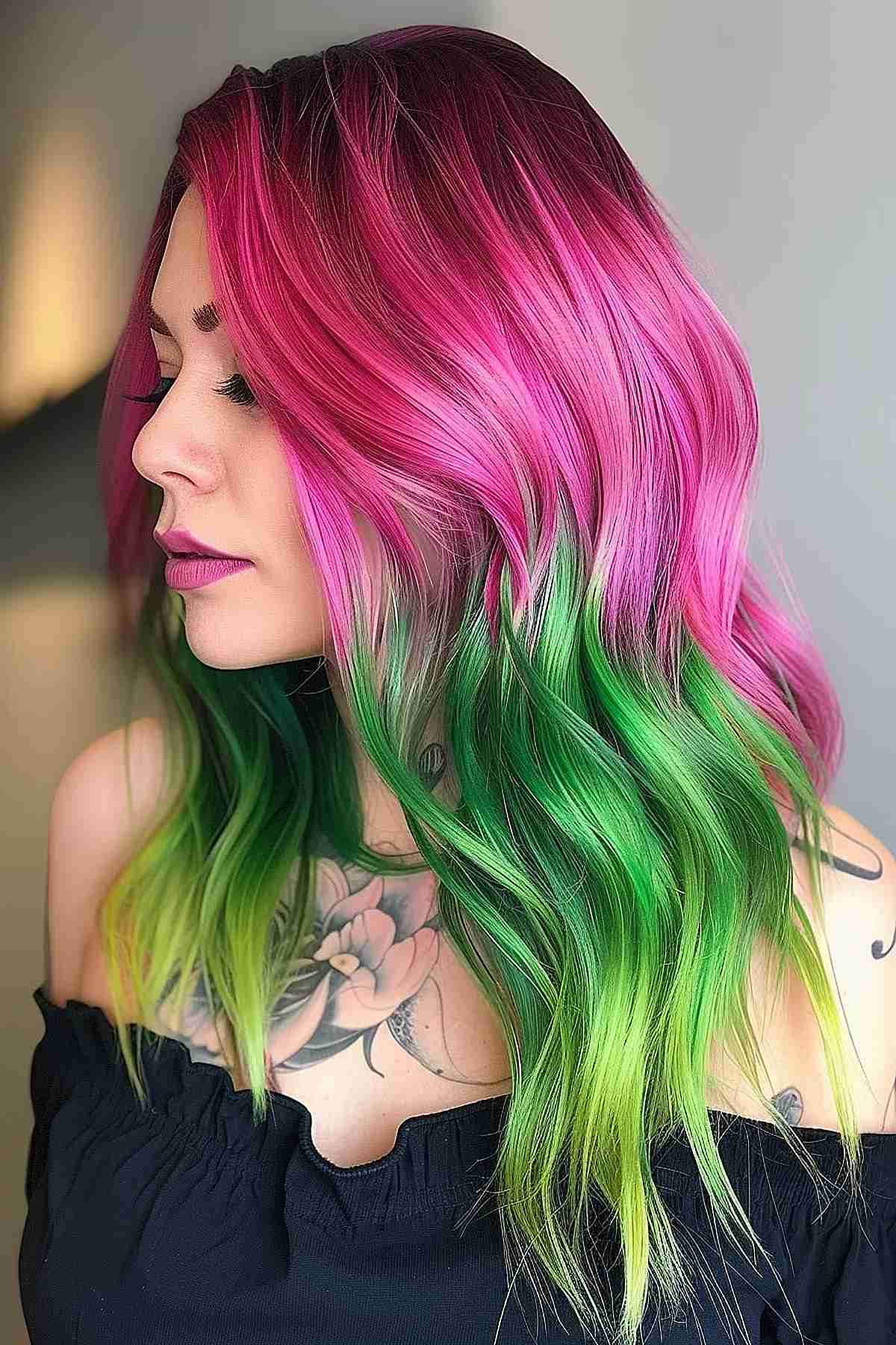 A woman with long wavy hair featuring a vibrant transition from deep magenta to bright lime green, embodying a bold and dramatic watermelon-inspired color scheme.