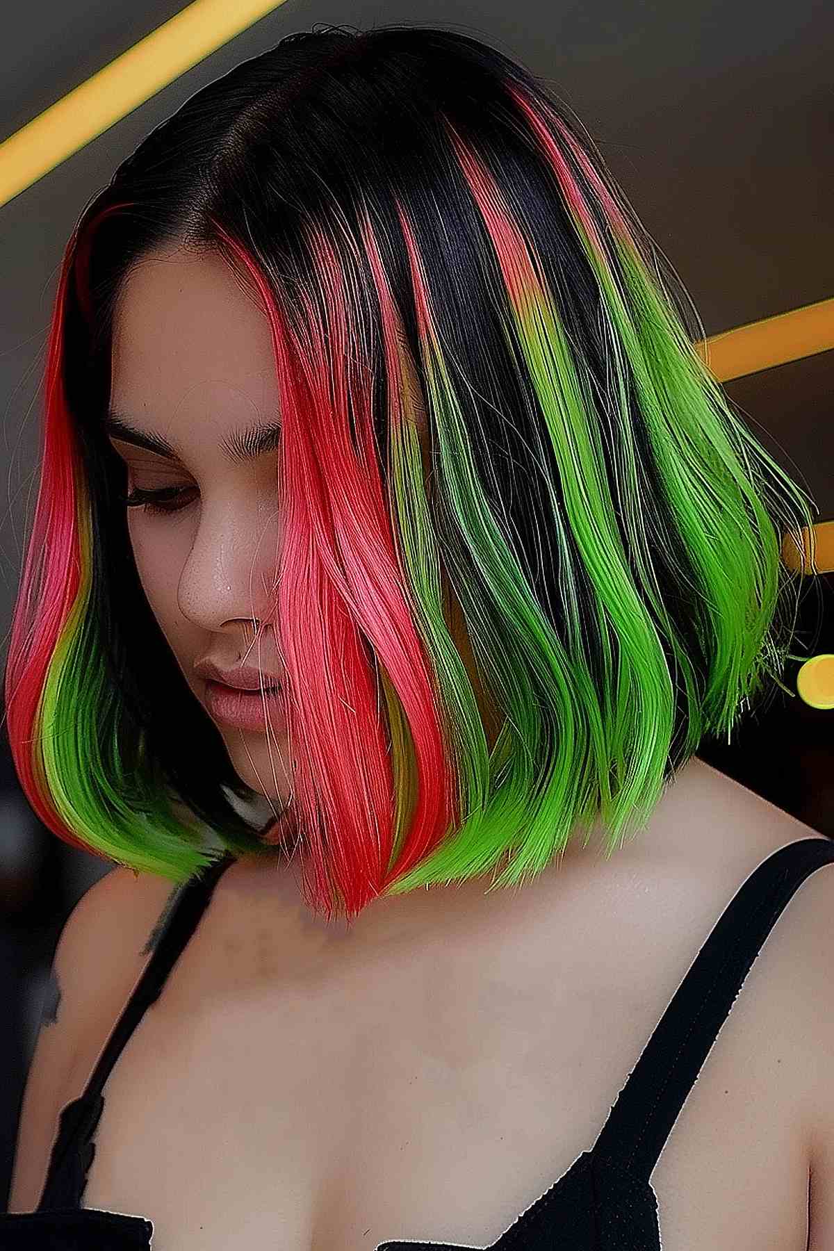 Short bob hairstyle featuring neon watermelon highlights with sharp contrast between neon green, vivid pink, and a deep black base, styled to showcase the dynamic color play. 