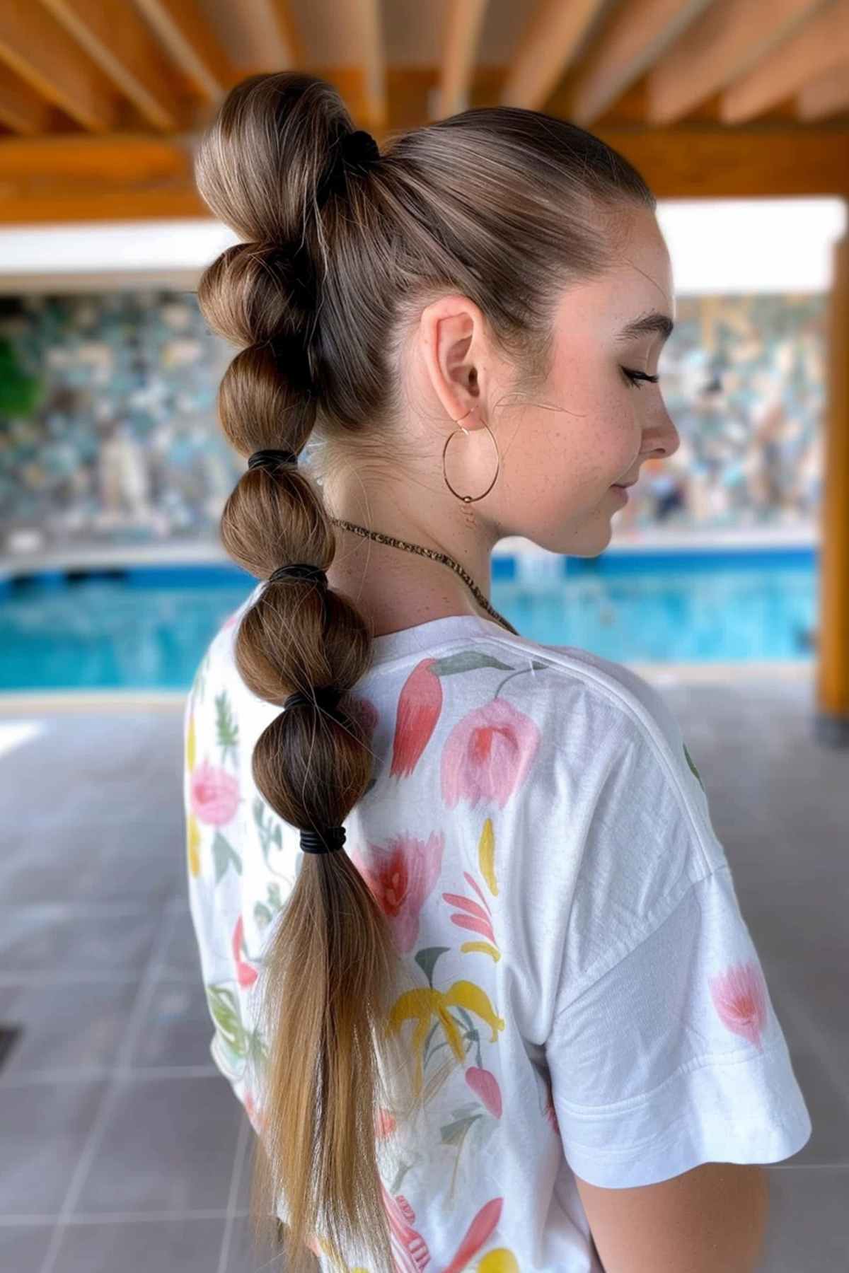 Side view of a woman with a bubble ponytail, ideal for long hair and adding a fun, trendy touch to a secure hairstyle at the waterpark