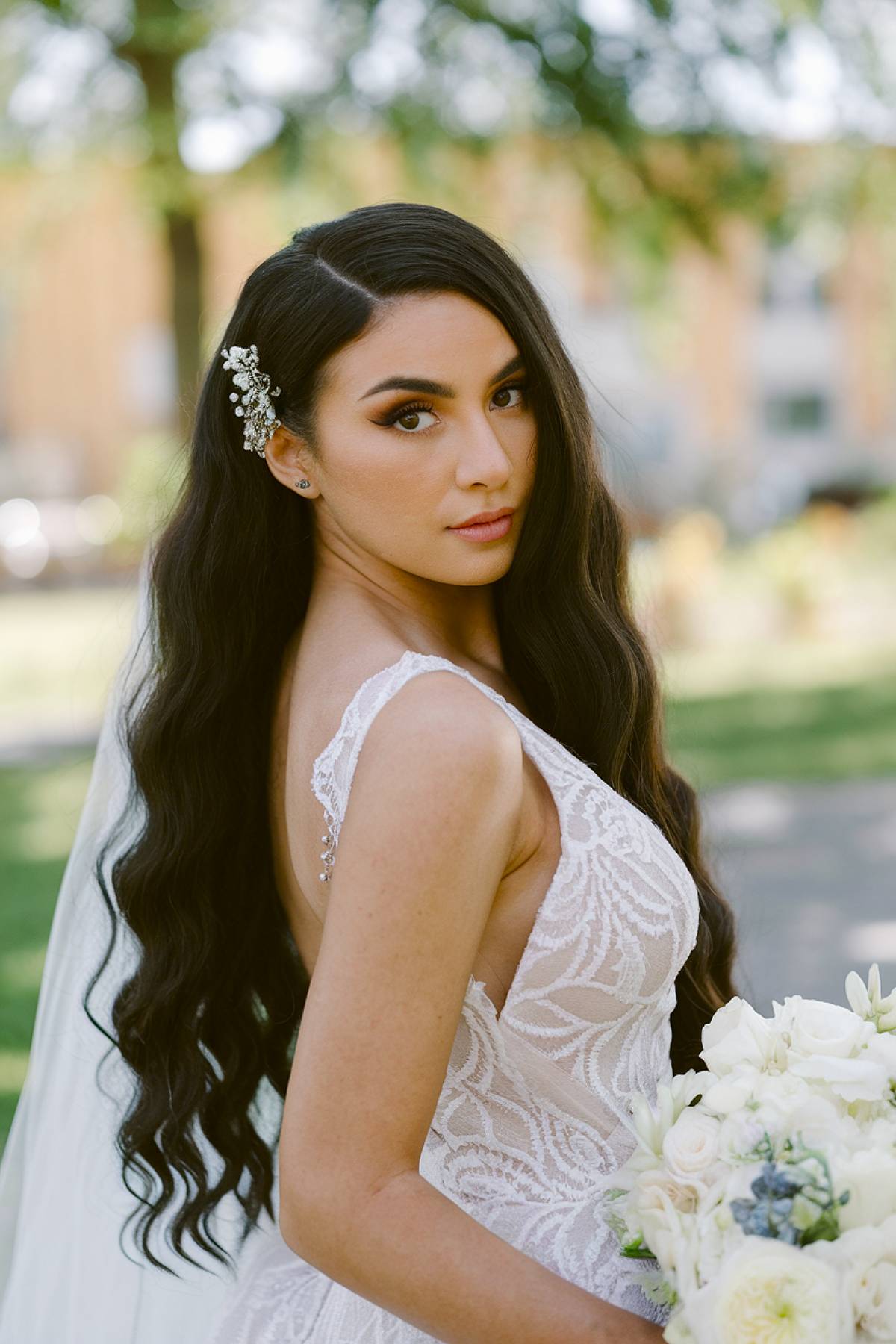 Long, glossy wedding waves with a deep side part and a jeweled hair accessory for a glamorous bridal look