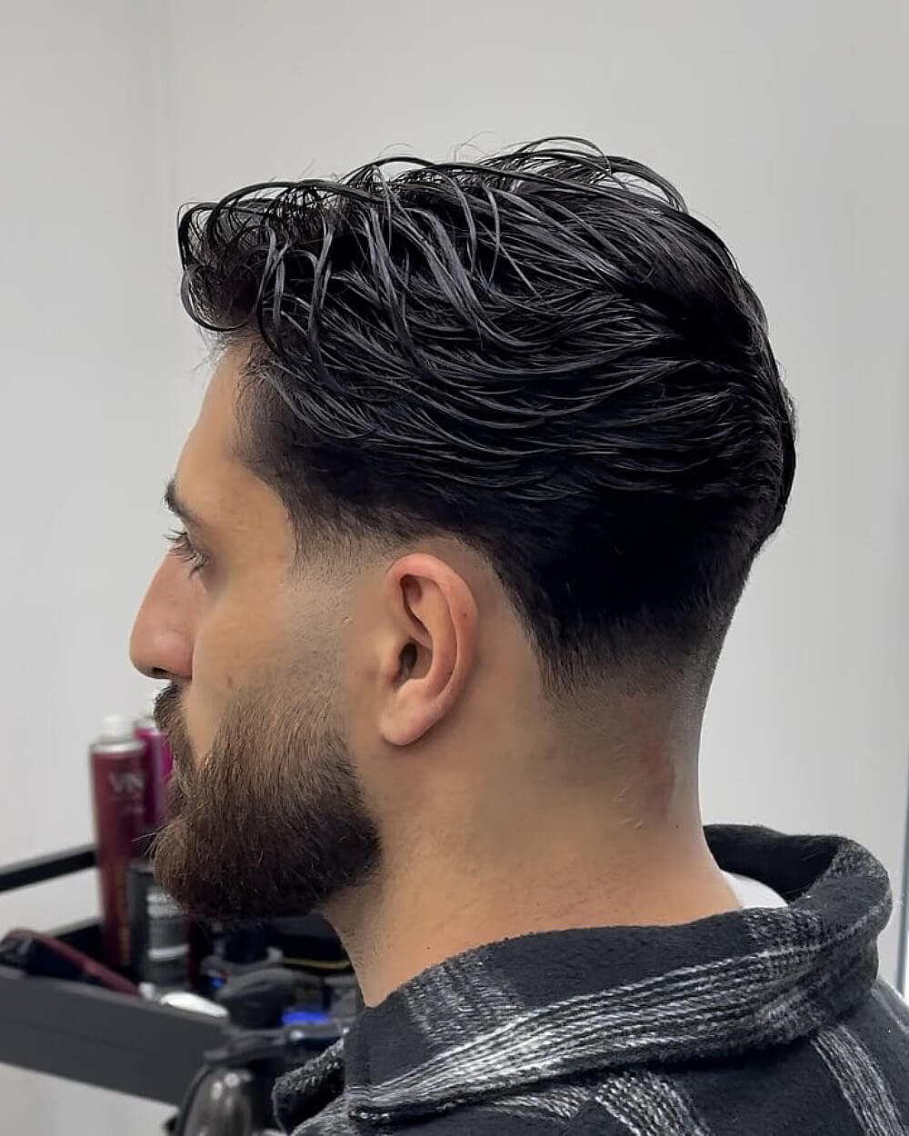 Wet comb back style with low taper fade on thick straight hair for a sleek finish