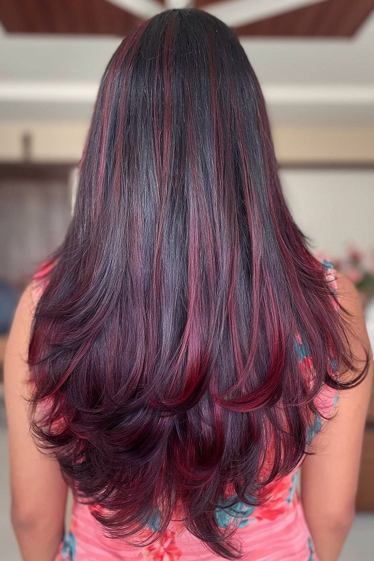 Wine red highlights on dark wavy hair